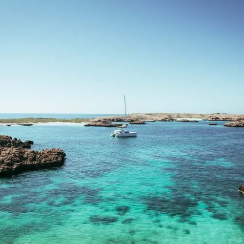 Un catamarano bianco ancorato nelle acque turchesi e trasparenti della riserva naturale delle Isole Daymaniyat in Oman.