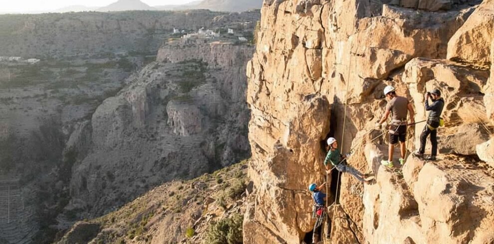Un escursionista affronta il percorso attrezzato della via ferrata sulle imponenti pareti rocciose di Jebel Shams, Oman.