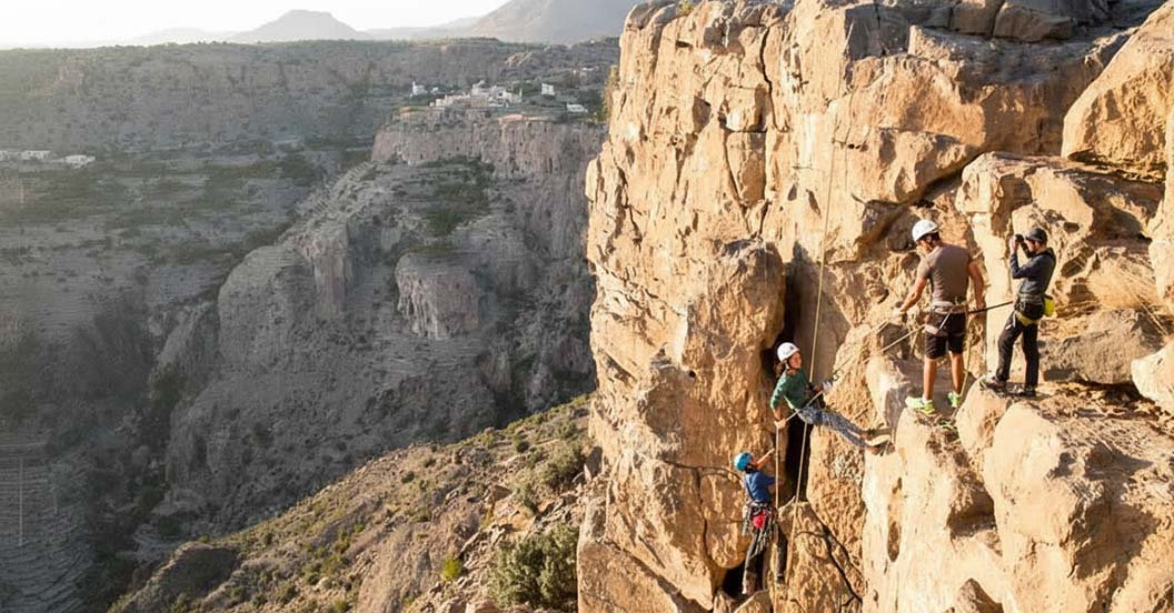 Un escursionista affronta il percorso attrezzato della via ferrata sulle imponenti pareti rocciose di Jebel Shams, Oman.