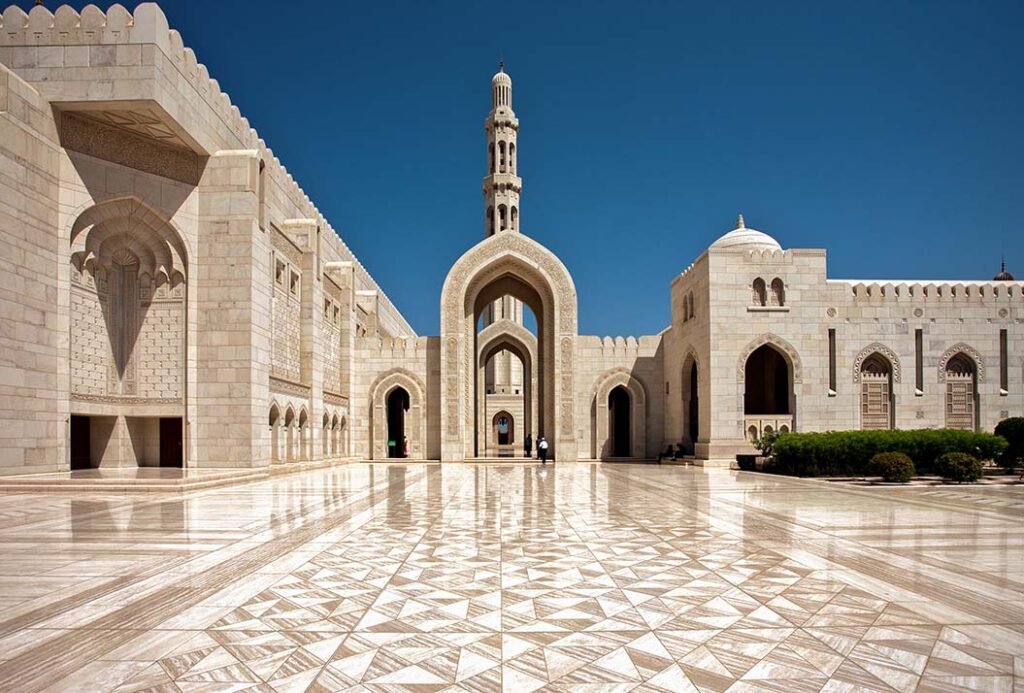L'imponente portale d'ingresso principale in pietra scolpita della Grande Moschea del Sultano Qaboos a Mascate, Oman.