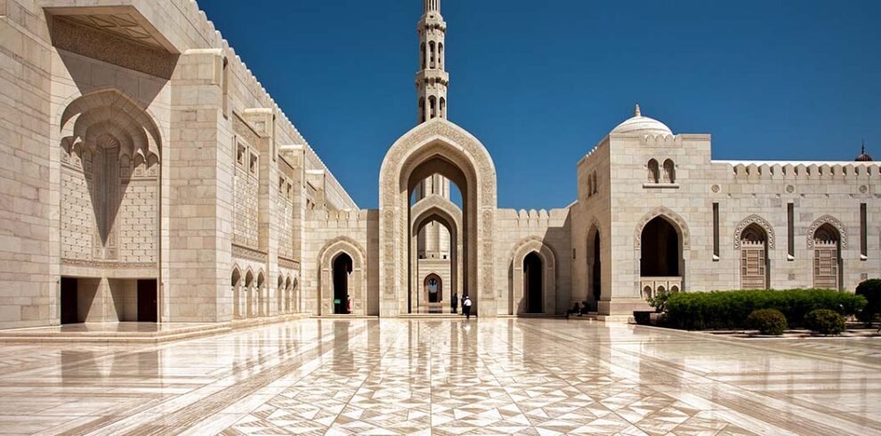 L'imponente portale d'ingresso principale in pietra scolpita della Grande Moschea del Sultano Qaboos a Mascate, Oman.