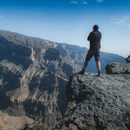 Un escursionista raggiunge la vetta del Jebel Shams, la montagna più alta dell'Oman a 3000 metri, lungo il sentiero W4 con vista sul Grand Canyon.