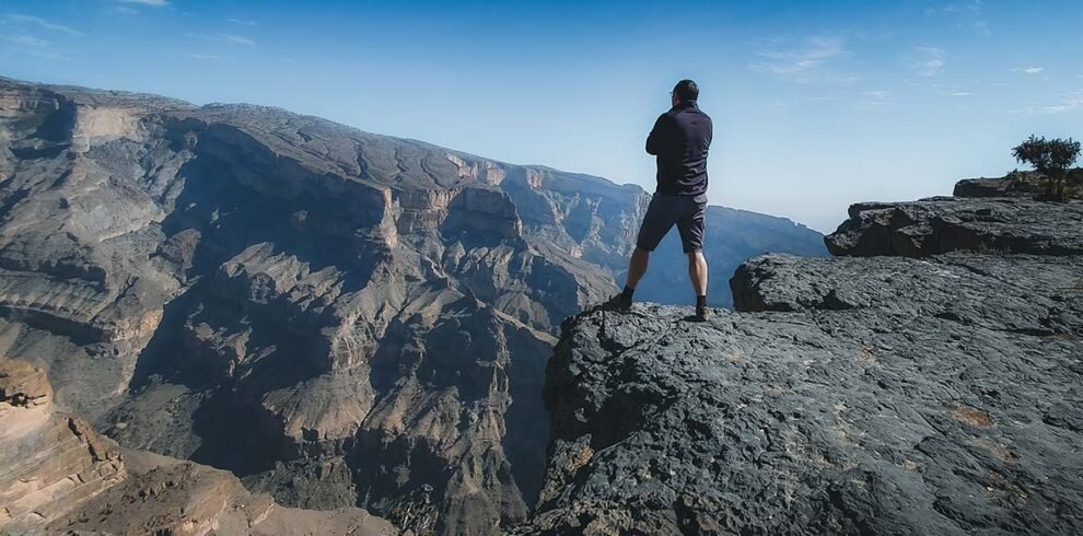 Un escursionista raggiunge la vetta del Jebel Shams, la montagna più alta dell'Oman a 3000 metri, lungo il sentiero W4 con vista sul Grand Canyon.