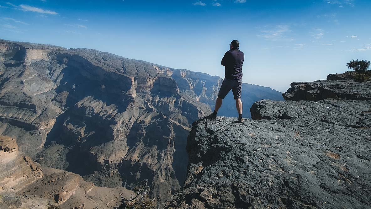 Un escursionista raggiunge la vetta del Jebel Shams, la montagna più alta dell'Oman a 3000 metri, lungo il sentiero W4 con vista sul Grand Canyon.